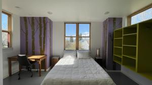 een slaapkamer met een bed, een bureau en ramen bij Stunning Modern Apartment, One Of A Kind! in Bozeman