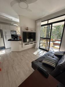 a living room with a couch and a television at Apto Riviera de São Lourenço com Piscinas Aquecidas,Quadra,Sacada Gourmet in Bertioga