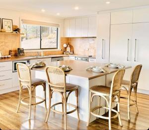 a kitchen with a large island with four chairs at The Gums - Bruny Island in Woodbridge