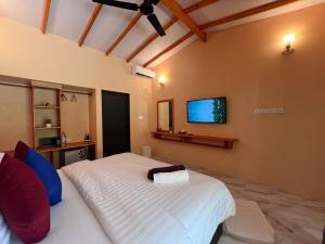 a bedroom with a large white bed and a flat screen tv at Blue Coral Thoddoo in Thoddoo