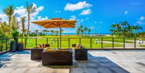 a patio with an umbrella and chairs and the beach at 家在银滩边 in Dianbailiao