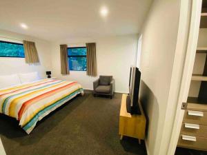 フランクトンにあるQueenstown Luxury Holiday Villaのベッドと椅子とテレビのある寝室