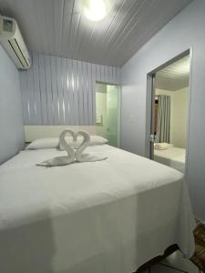 a large white bed with a heart decoration on it at Casa na Praia Araçá in Bombas