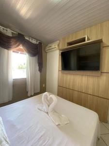 a room with a bed with a heart shaped towel at Casa na Praia Araçá in Bombas