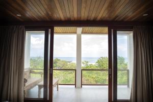 a room with sliding glass doors with a view of the ocean at Bali Natha Beach Front in Canggu