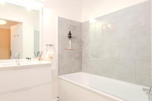 a white bathroom with a tub and a sink at Agapé by Kleidos -Disney à 10min, T2 , 4P, Parking gratuit et terrasse in Magny-le-Hongre +41 photos