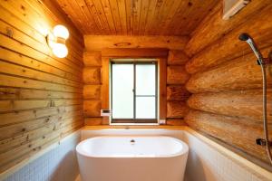 a bathroom with a white tub in a wooden wall at S-villa Karuizawa Muguet in Hoshina