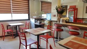 イロイロにあるPearLi View Hotel Iloilo powered by Cocotelの赤い椅子とテーブル、カウンター付きのレストラン