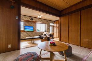 a living room with a table and a couch at 貸別荘TANoSHI-SA- in Jahana