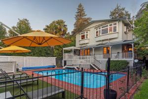 a house with a pool and an umbrella at Camellia House - Elevator Access, Swimming, and Spa Pools in Nelson