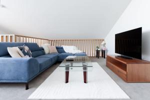 a living room with a blue couch and a tv at Cosy Riverside Escape with River Views in Inveresk