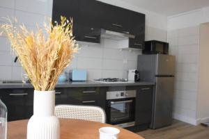 a kitchen with a table with a vase with grass at L'escapade, entièrement rénové, proche centre in Grenoble