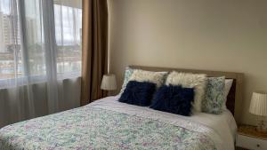 une chambre avec un lit avec des oreillers bleus et une fenêtre dans l'établissement Departamento Jardines del Pacifico, à La Serena