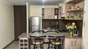 Il comprend une cuisine équipée d'un comptoir avec des chaises et d'un réfrigérateur. dans l'établissement Departamento Jardines del Pacifico, à La Serena