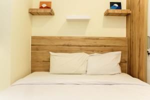 a bedroom with a bed with a wooden headboard at Cozy Living and Tidy 1BR Meikarta Apartment By Travelio in Cikarang