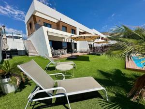 a group of chairs and tables in front of a building at Villa Finestrat Benidorm Golf y Playa in Cala de Finestrat