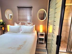 a bedroom with a bed and two mirrors on the wall at URlyfstyle Cottage 10km from OR Tambo Int Airport in Kempton Park +30 photos