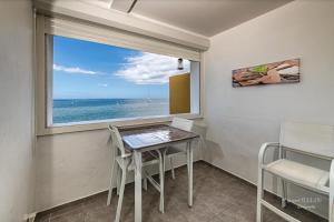une table et des chaises dans une pièce avec une fenêtre dans l'établissement L'heure Dorée - Charmant appartement vue mer, à Saint-Pierre