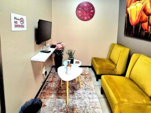 a living room with a couch and a table and a clock at URlyfstyle Cottage 10km from OR Tambo Int Airport in Kempton Park
