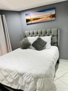 een slaapkamer met een wit bed met 2 kussens bij West Home Rest in Westonaria