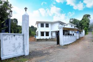 a white house with a clock tower next to a dirt road at Angel Valley Inn in Vayittiri +8 photos