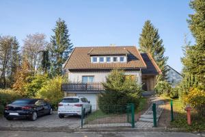a house with two cars parked in a driveway at Fewo Harzwichtel am Waldesrand in Braunlage