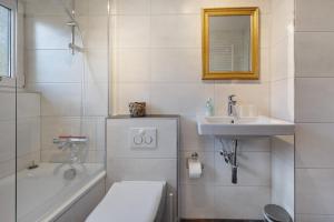 a bathroom with a toilet and a sink and a tub at Fewo Harzwichtel am Waldesrand in Braunlage +20 photos