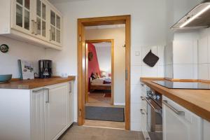 a kitchen with white cabinets and a door leading to a living room at Fewo Harzwichtel am Waldesrand in Braunlage
