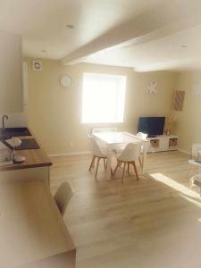 a living room with a table and white chairs at La Pluméria Appartement 2 chambres in Saint-Germain-Lespinasse