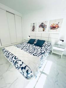 a white bedroom with a large bed with blue pillows at Apartamento Aljaralto Sevilla in San Juan de Aznalfarache