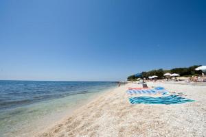 einen Strand mit Stühlen und Sonnenschirmen und dem Wasser in der Unterkunft Apartments Cvek in Rovinj