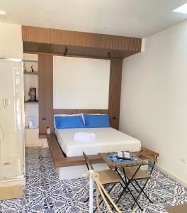 Schlafzimmer mit einem Bett mit blauen Kissen und einem Tisch in der Unterkunft Alisa suite in Mercato San Severino
