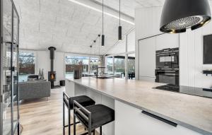 a kitchen with a large counter with stools at Amazing Home In Væggerløse With Sauna in Marielyst +14 photos