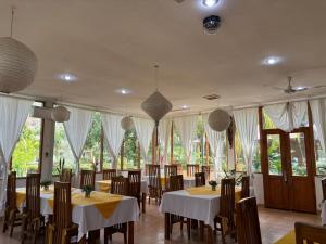 a dining room with tables and chairs and windows at Palm Malinamoc Hotel in Dili