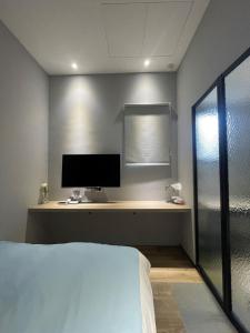una camera da letto con un letto e una scrivania con un monitor di 蘆思特六合民宿 a Kaohsiung