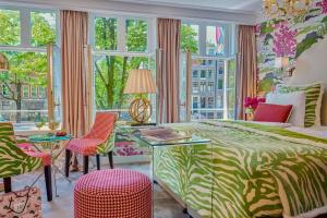a bedroom with a bed and chairs and windows at Hotel Estheréa in Amsterdam