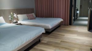 two beds in a hotel room with wood floors at 蘆思特六合民宿 in Kaohsiung
