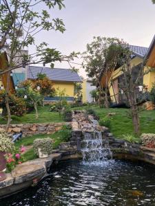 a pond with a waterfall in a yard at Linh Anh Homestay MC - by BAY LUXURY in Mộc Châu