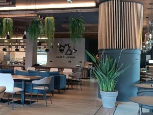 a restaurant with tables and chairs and potted plants at Zlatni javor Apartman 401 in Jahorina