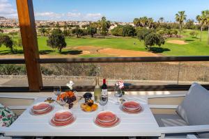 a table with plates of food and a view of a golf course at Casa Paraiso in Caleta De Fuste