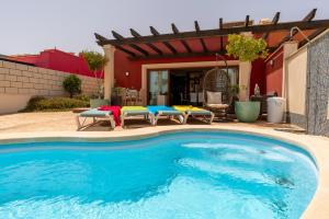 a swimming pool in front of a house at Villa V8 in Caleta De Fuste