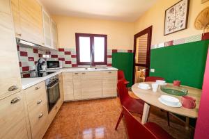 een keuken met een tafel en stoelen en een groene muur bij Casa Carola - Bahia Sol in Caleta De Fuste