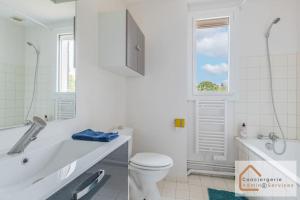 e bagno bianco con servizi igienici, vasca e lavandino. di Maison Évasion - Piscine, Jardin & Barbecue a Oullins Altre 16 foto