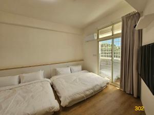 two beds in a room with a large window at Dessert No8 Homestay in Beinan