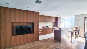 a kitchen with wooden cabinets and a flat screen tv at Apartament F&M in Braga +14 photos
