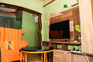 a living room with an orange chair and a television at Amazing Grace Homes ( AG Homes) in Oyugis