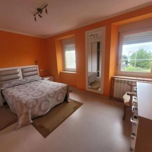 a bedroom with orange walls and a bed and a mirror at Casa Viqueira in Foz