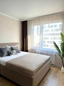TaldykolʼにあるEasy Apartのベッドと大きな窓のある寝室
