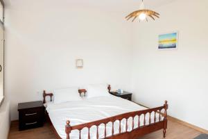 a bedroom with a bed with white sheets and a chandelier at Слънчевите Къщи-село Китка in Kitka +33 photos