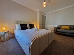 ein Schlafzimmer mit einem großen Bett und einer Couch in der Unterkunft Stylish and Modern 7 Bedroom house near Brecon Beacons in Cefn-coed-y-cymmer